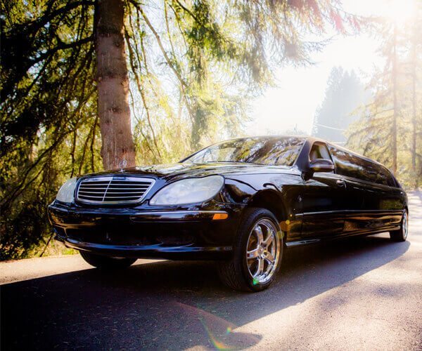 Luxury black Mercedes limousine on a scenic road